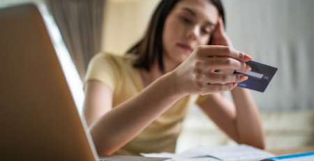 Mulher estressada olhando o cartão de crédito
