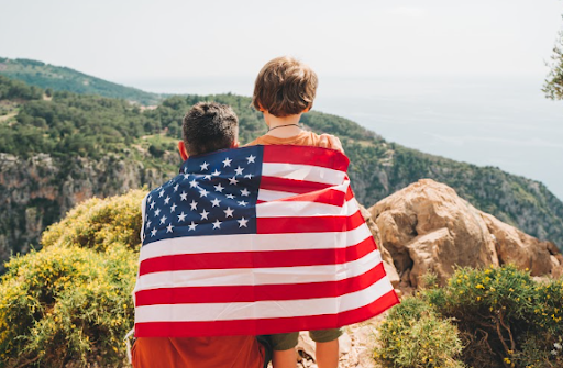 Pai e filho com a bandeira dos EUA olhando a paisagem