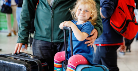 Criança sentada em cima de mala em aeroporto