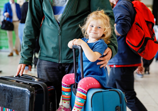 Criança sentada em cima de mala em aeroporto