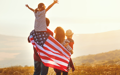 Família com a bandeira dos EUA nas costas observando o sol
