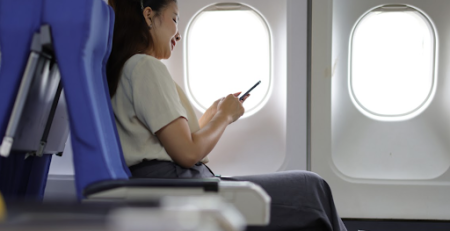 Mulher em avião vendo no celular visto de transito
